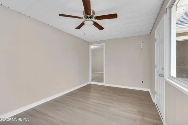 an empty room with wooden floor fan and windows