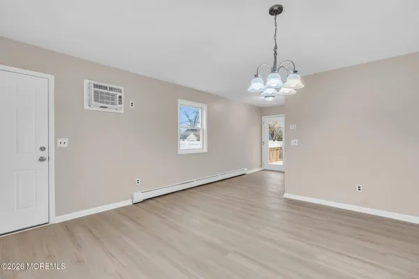 a view of an empty room with wooden floor and windows
