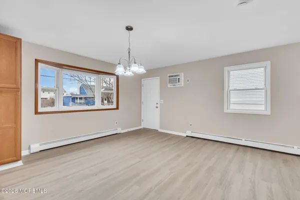 an empty room with wooden floor chandelier and windows
