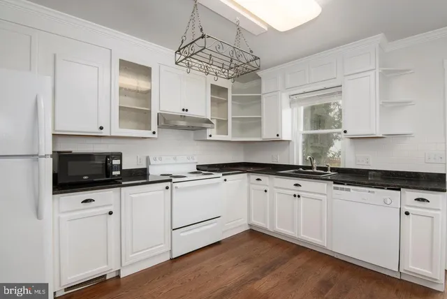 a kitchen with stainless steel appliances granite countertop a sink and cabinets with wooden floor