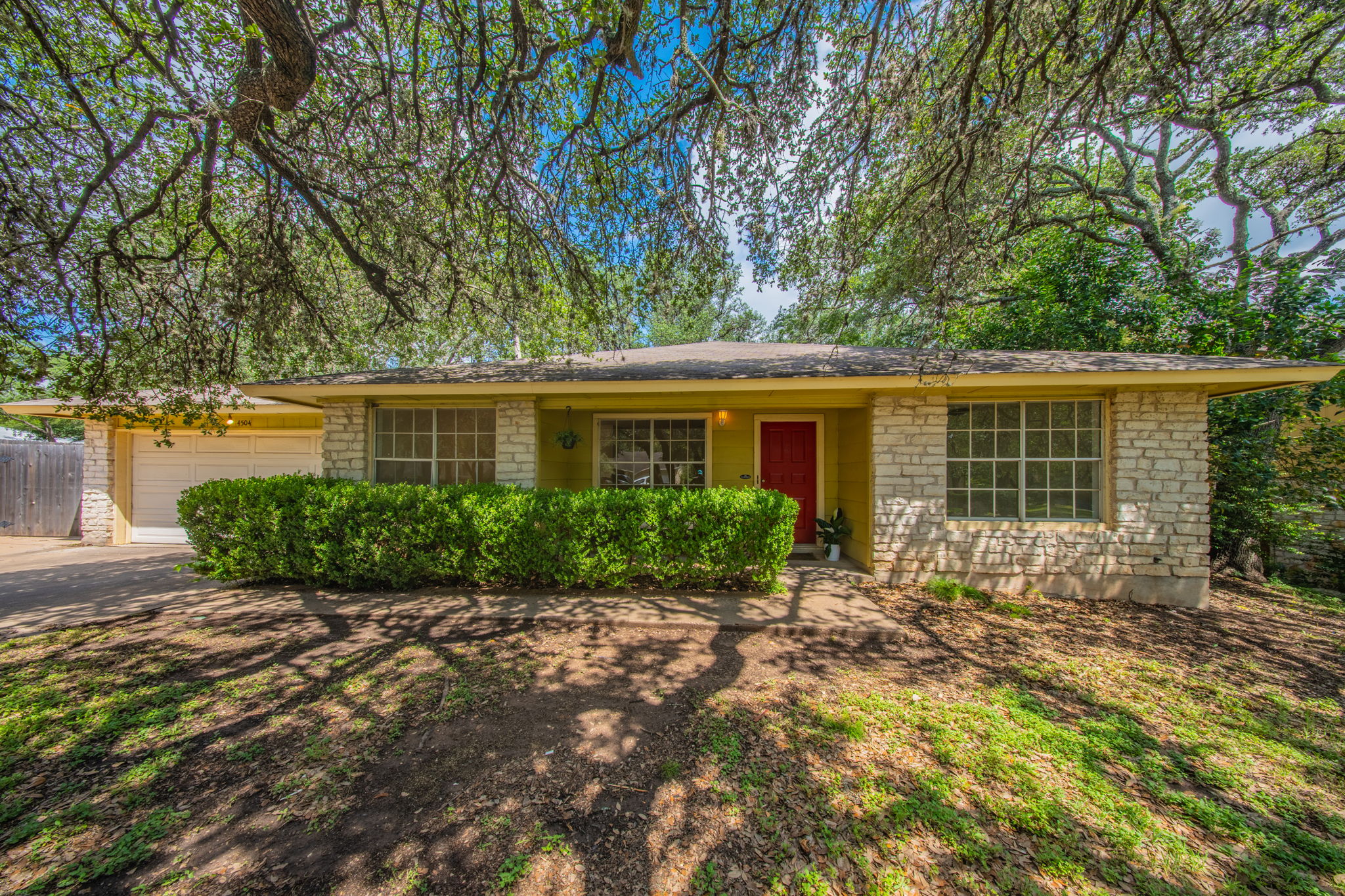 4504 Langtry Lane Austin, TX 78749 - Photo 23 of 24 Mature trees shade this charming facade, featuring a red entry door and an attached garage.