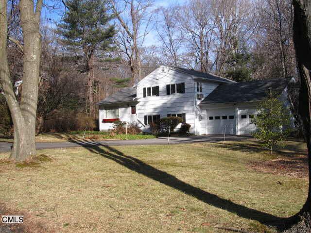 a front view of a house with a yard and a large tree