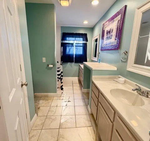 a spacious bathroom with a granite countertop sink a mirror and bathtub
