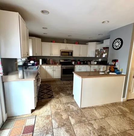 a kitchen with stainless steel appliances granite countertop a stove top oven a sink a microwave and cabinets