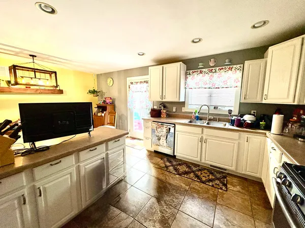 a large white kitchen with stainless steel appliances a stove a sink a microwave and cabinets