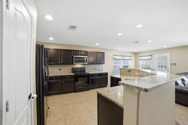 a kitchen with stainless steel appliances granite countertop a sink dishwasher stove top oven and refrigerator