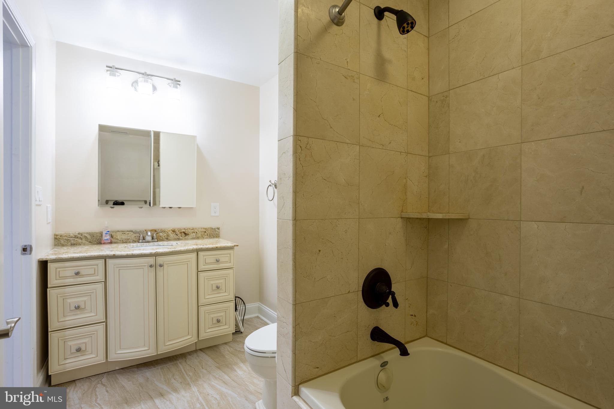 7908 Ivy Lane Baltimore, MD 21208 - Photo 37 of 90 a bathroom with a granite countertop sink a mirror and shower