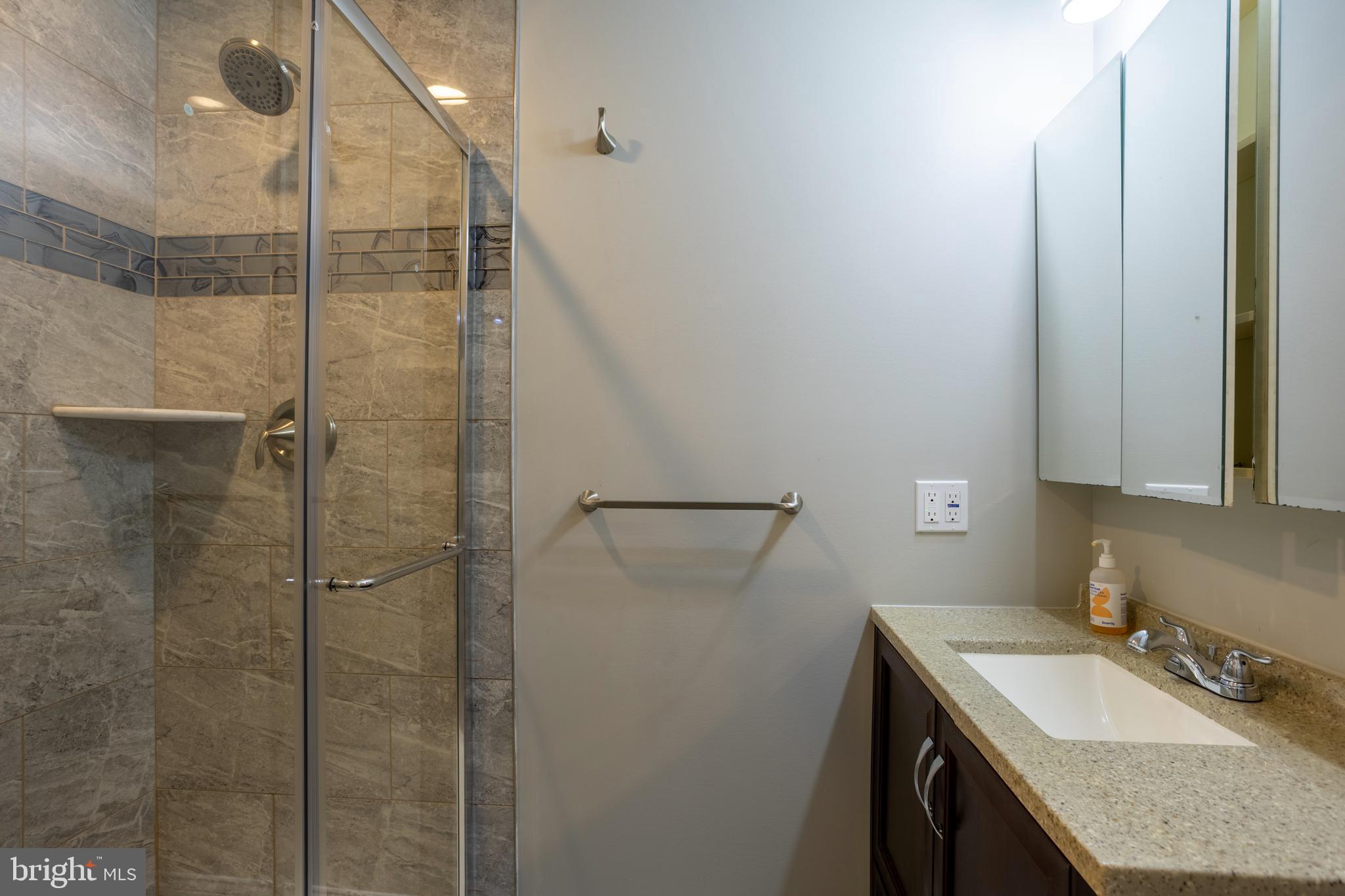 7908 Ivy Lane Baltimore, MD 21208 - Photo 59 of 90 a bathroom with a granite countertop sink a mirror and shower