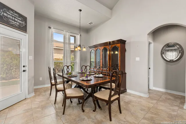 a view of a dining room and livingroom with furniture wooden floor a rug a painting and a chandelier