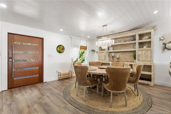 a dining room with stainless steel appliances kitchen island granite countertop a dining table chairs and a refrigerator