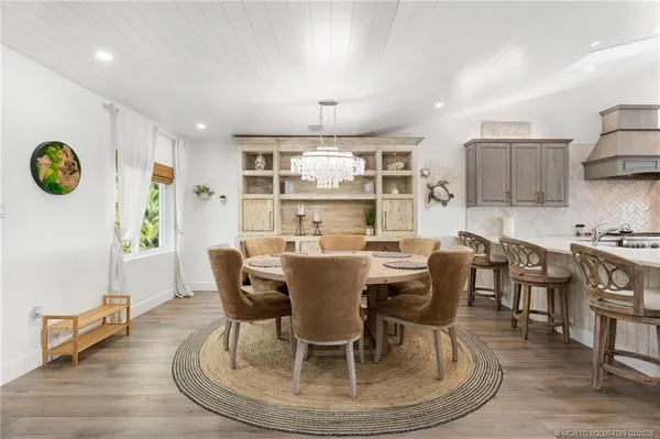 a kitchen with stainless steel appliances a table chairs in it and wooden floors