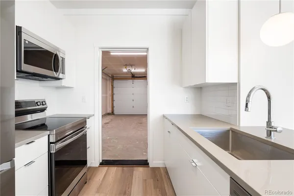 a kitchen with a sink and a stove top oven with wooden floor