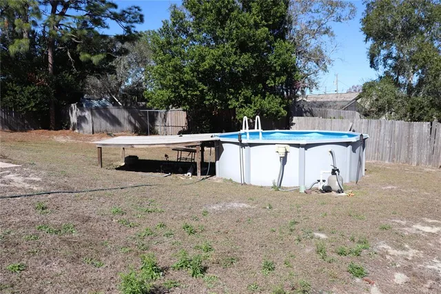 a view of backyard with seating space and trees in the background