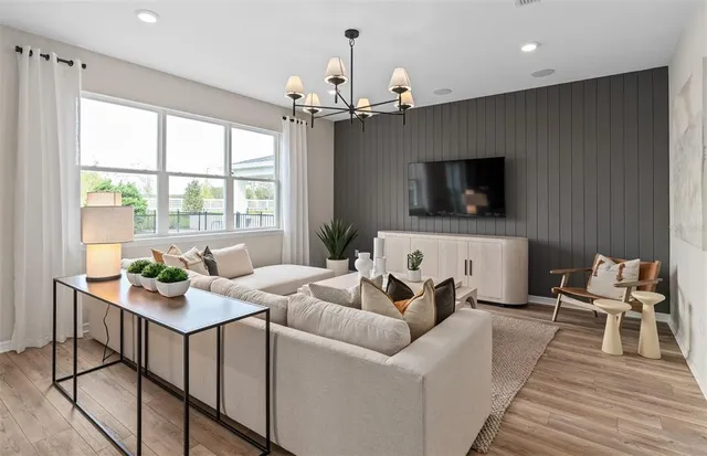a living room with furniture a flat screen tv and a chandelier