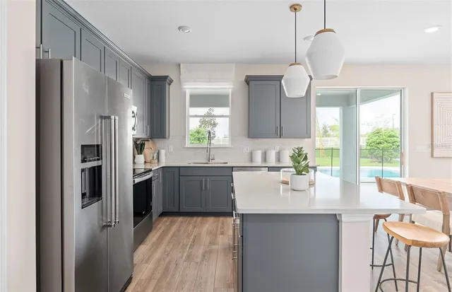 a kitchen with stainless steel appliances granite countertop a sink a stove a refrigerator cabinets a dining table and chairs