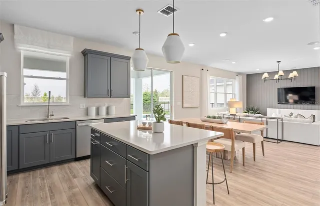 a kitchen with a refrigerator a stove a sink and dishwasher with wooden floor