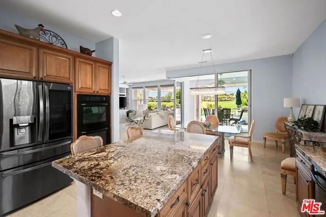 a kitchen with stainless steel appliances granite countertop a sink a stove a refrigerator cabinets and living room view