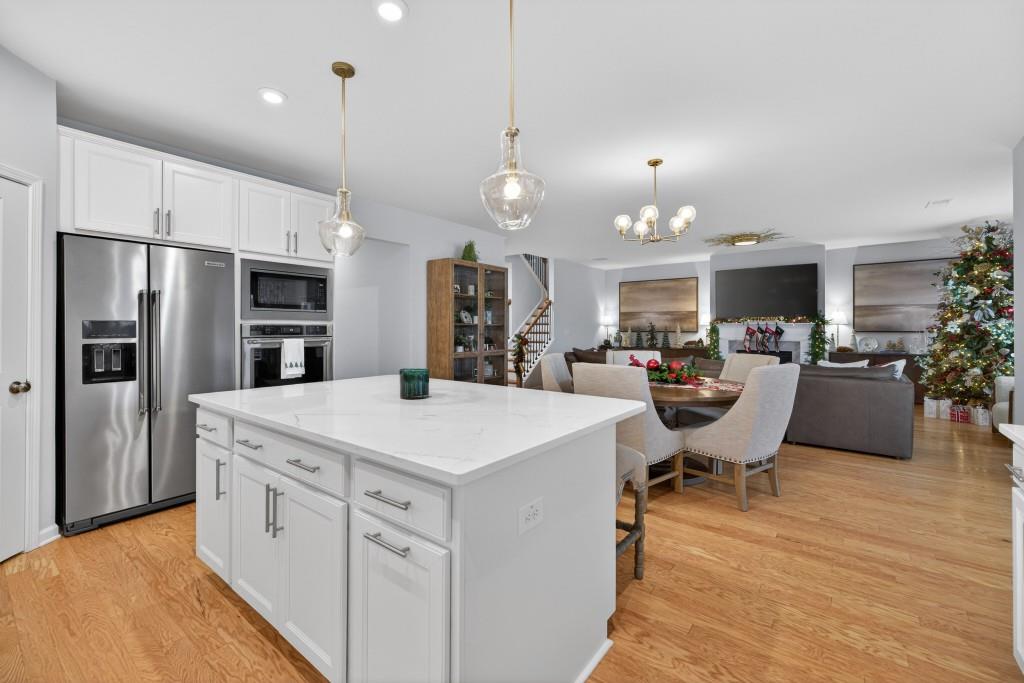 7277 Maple Brook Lane Flowery Branch, GA 30542 - Photo 22 of 93 a large kitchen with kitchen island a refrigerator a stove a sink a dining table and chairs
