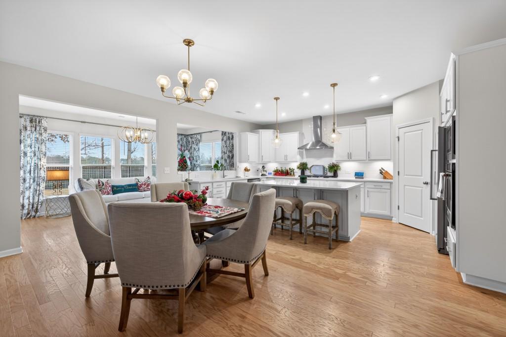 7277 Maple Brook Lane Flowery Branch, GA 30542 - Photo 26 of 93 a dining room with kitchen island stainless steel appliances furniture large window and wooden floor