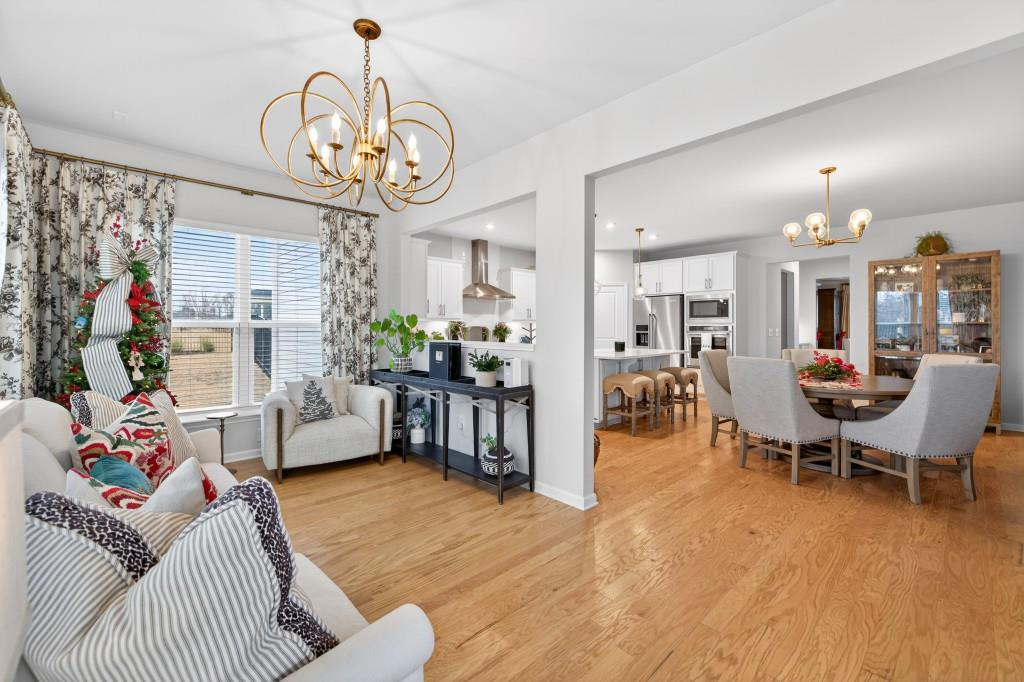 7277 Maple Brook Lane Flowery Branch, GA 30542 - Photo 30 of 93 a living room with furniture a chandelier and a dining room
