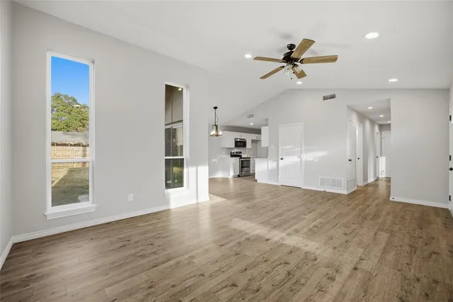 a view of empty room with wooden floor and windows