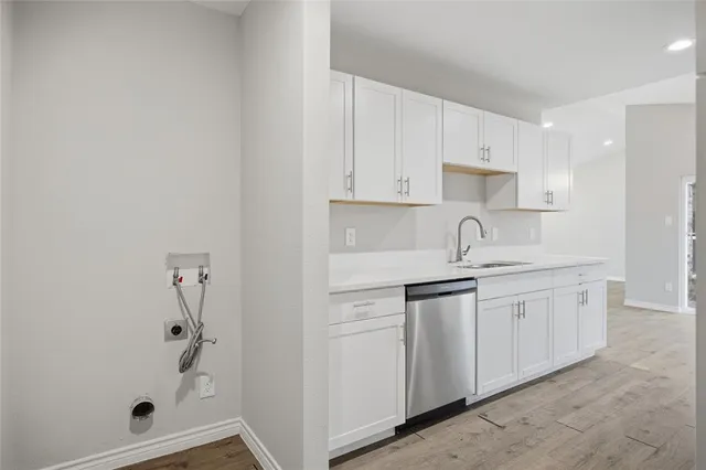 a kitchen with white cabinets and sink