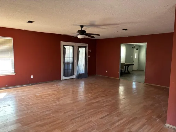 a view of an empty room with window and wooden floor