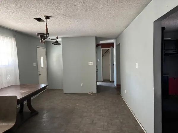 a view of a room with a hanging light and hardwood