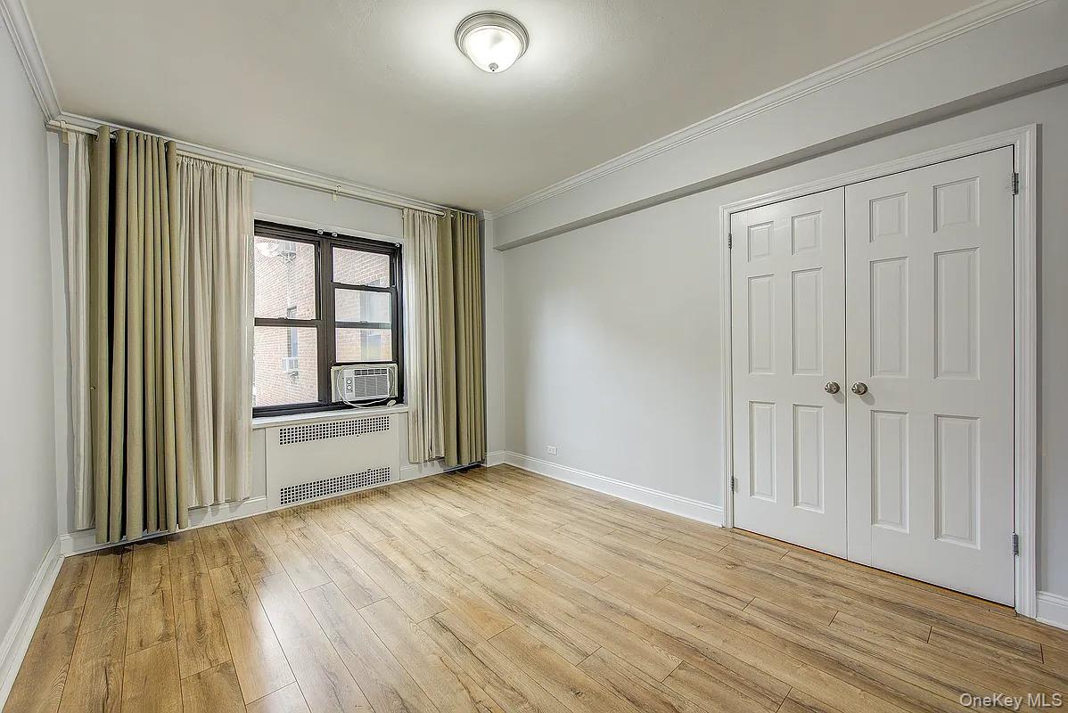 67-76 Booth Street, Unit 4F Queens, NY 11375 - Photo 21 of 33 an empty room with wooden floor and windows