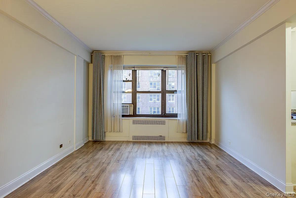 67-76 Booth Street, Unit 4F Queens, NY 11375 - Photo 7 of 33 an empty room with wooden floor and windows