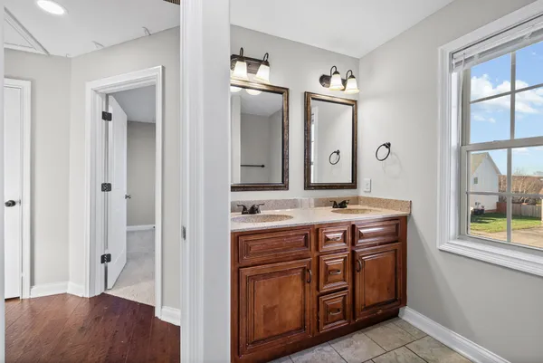 a view of bathroom with a sink mirror and window