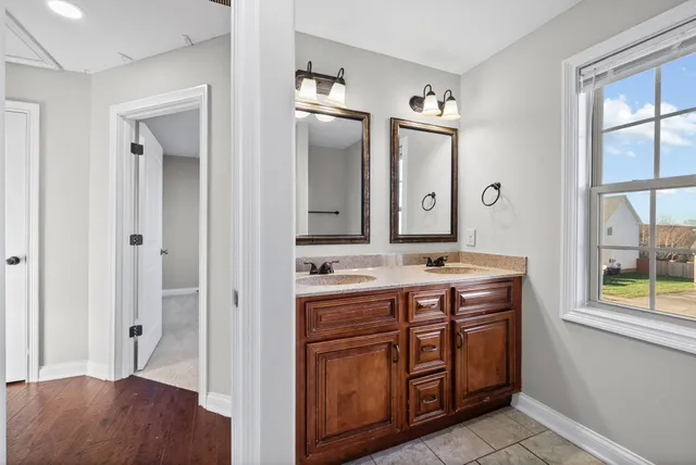 a view of bathroom with a sink mirror and window