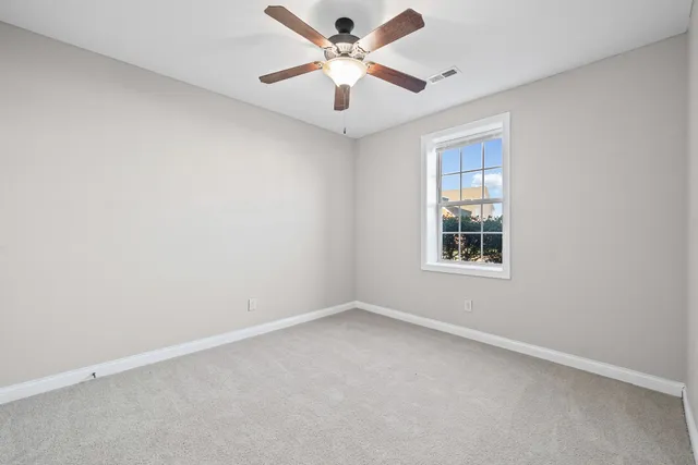 an empty room with windows and ceiling fan