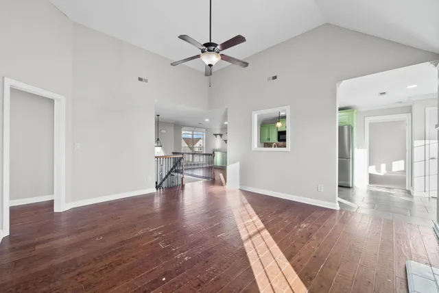 a view of an empty room with wooden floor and a ceiling fan