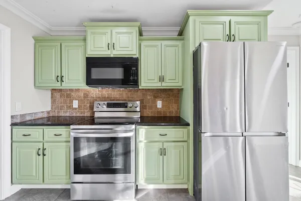 a kitchen with granite countertop a refrigerator and a stove top oven