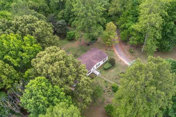 an aerial view of residential house with outdoor space and trees all around