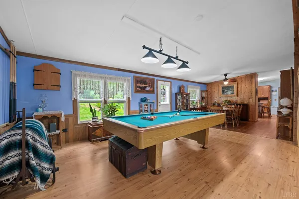 a room with furniture pool table wooden floor and windows
