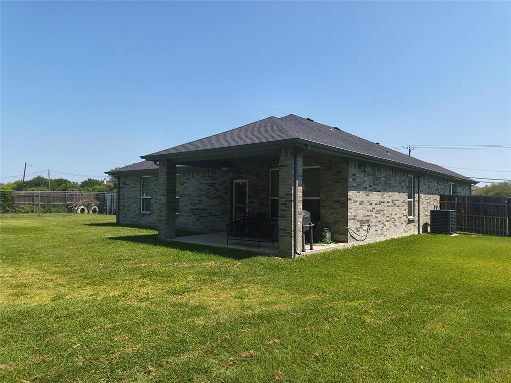 3027 Ames Road Lancaster, TX 75134 - Photo 30 of 35 Spacious backyard featuring a covered patio, brick exterior, dark shingle roof, and a wood privacy fence