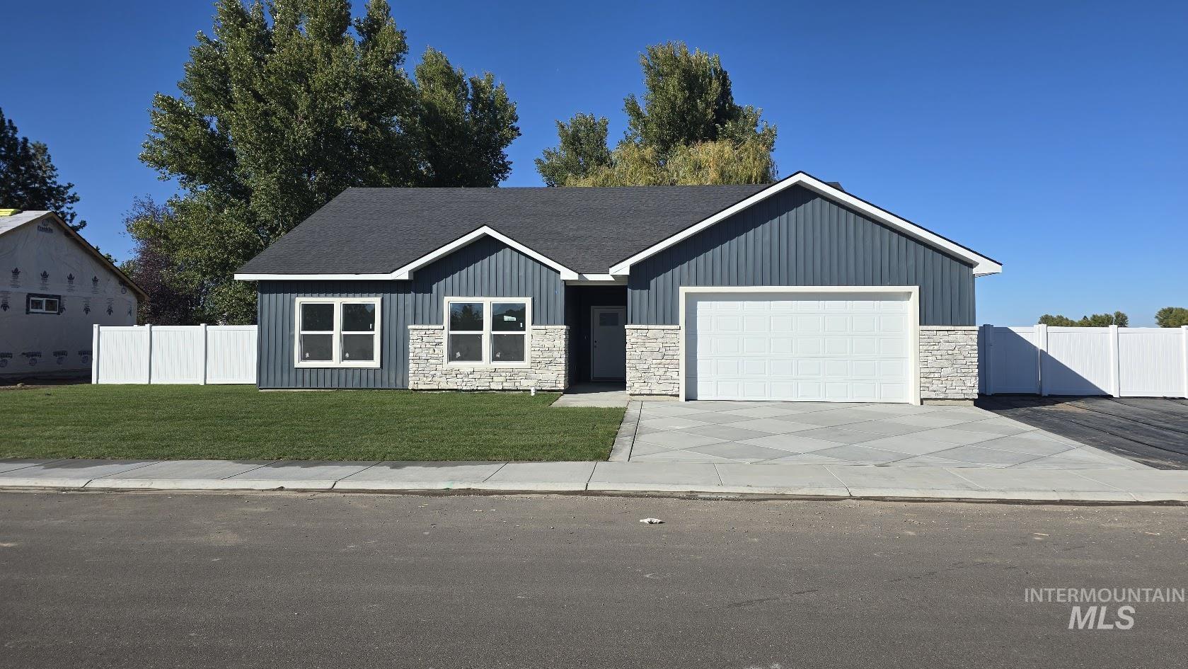 View of front of house featuring stone siding, driveway, a garage, and board and batten siding