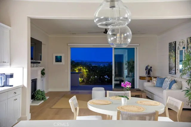 a view of a dining room with furniture a chandelier and large windows