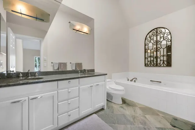 a bathroom with a granite countertop toilet a sink and a bathtub