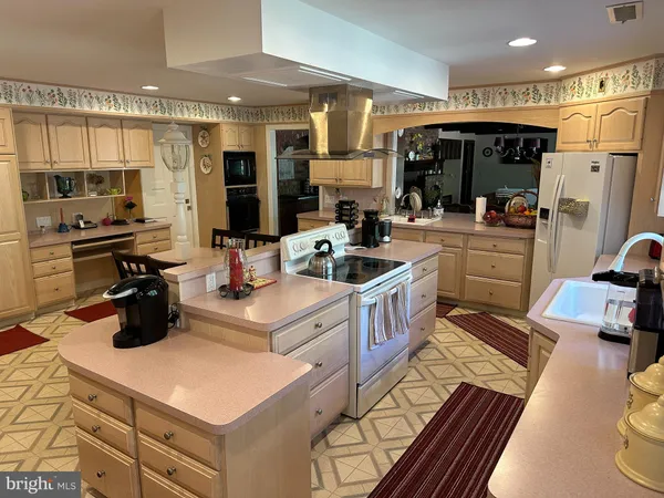 a kitchen with stainless steel appliances kitchen island granite countertop a sink refrigerator and cabinets