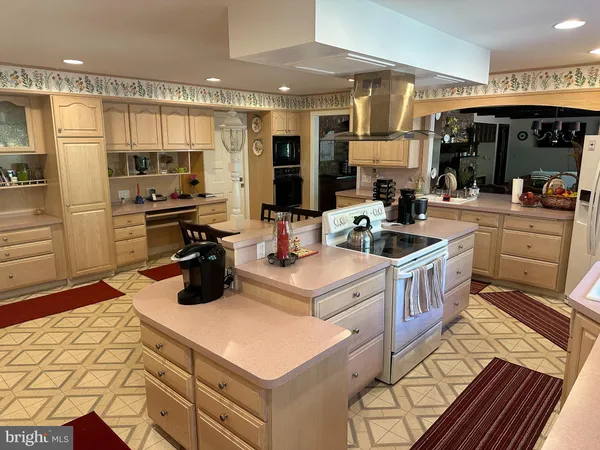 a kitchen with stainless steel appliances granite countertop a sink dishwasher a refrigerator a stove and a dining table with wooden floor