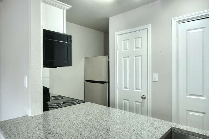 107 Castleberry Court, Unit D Bertram, TX 78605 - Photo 7 of 13 Kitchen with stainless steel refrigerator, white cabinetry, light stone counters, and stove