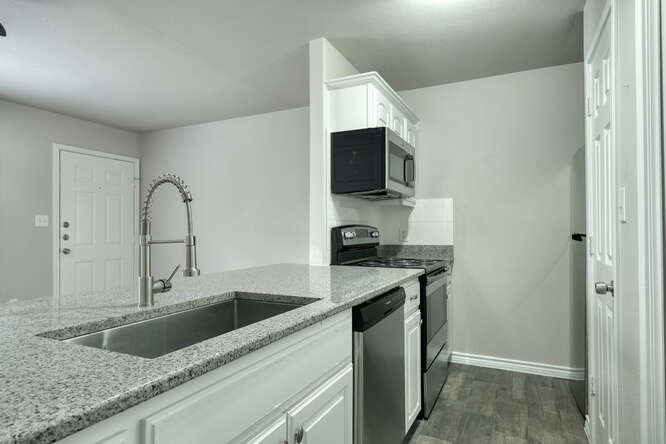 107 Castleberry Court, Unit D Bertram, TX 78605 - Photo 8 of 13 Kitchen featuring sink, dark wood-type flooring, stainless steel appliances, light stone countertops, and white cabinets