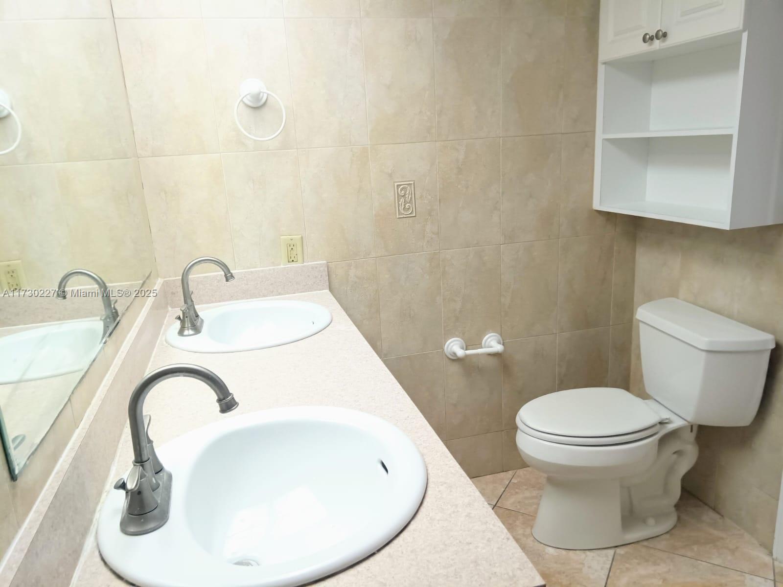 7348 Southwest 82nd Street, Unit C217 Miami, FL 33143 - Photo 14 of 19 a bathroom with a toilet sink and mirror