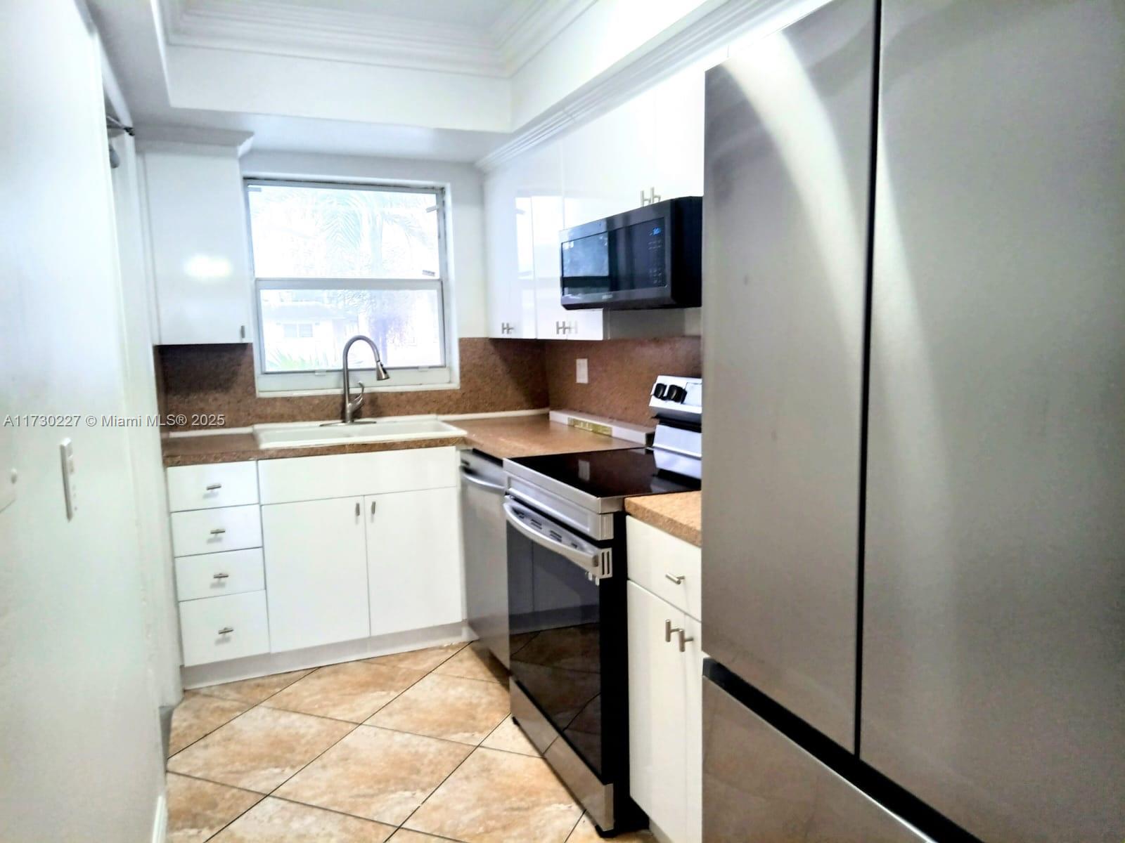 7348 Southwest 82nd Street, Unit C217 Miami, FL 33143 - Photo 2 of 19 a kitchen with a sink stove and microwave