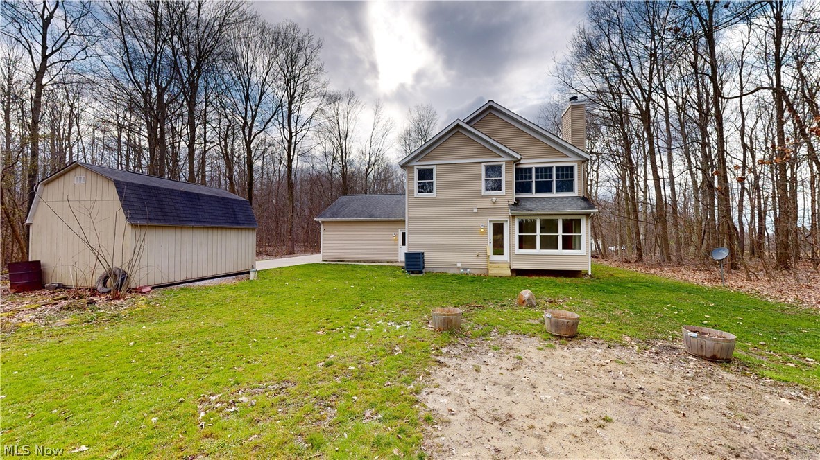 15548 Trask Road Thompson, OH 44086 - Photo 30 of 31 Back of house featuring a lawn, an outdoor structure, and central AC unit