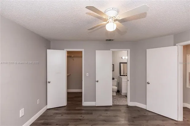 an empty room with wooden floor and ceiling fan