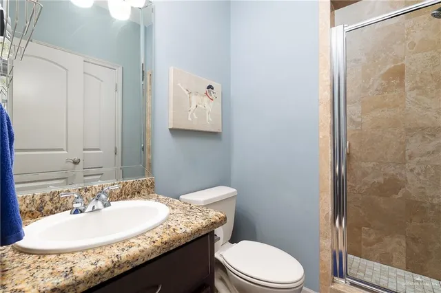 a bathroom with a granite countertop sink a toilet and shower